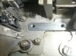 a flat bar with 2 screw holes sitting on a layered metal back plate with complex mechanisms above it